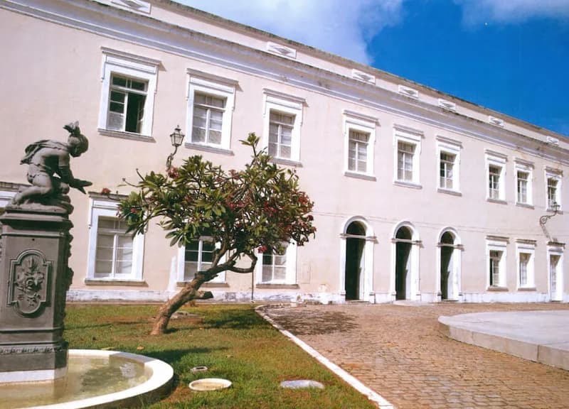Casario colonial branco com arcos e estátua sobre pedestal, patrimônio registrado no livro Caminhos da Arte, case HOUSECULTURA