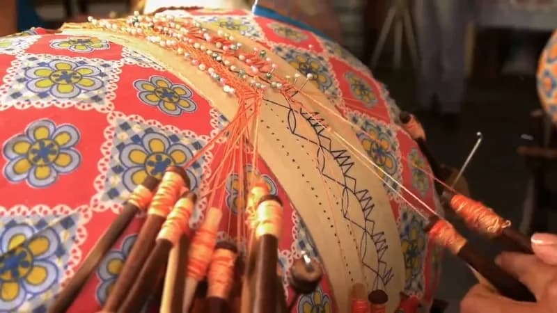 Almofada de renda em produção, com bilros laranja e o desenho a lápis, websérie DôMóValô da HOUSECULTURA