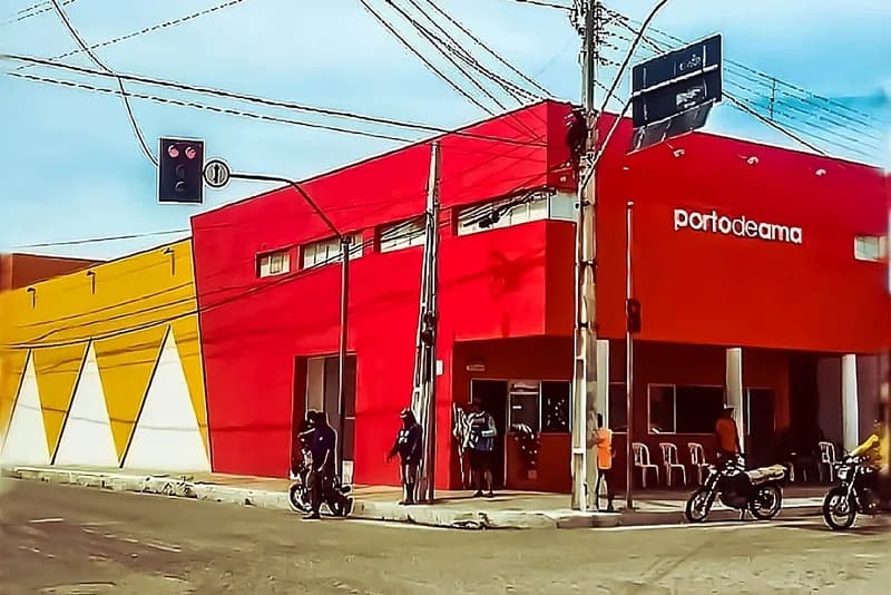 Prédio vermelho e amarelo do Porto de Ama na esquina, com pessoas na calçada, case HOUSECULTURA