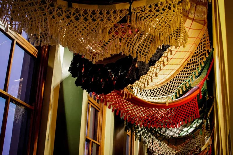 Redes de tear coloridas penduradas e vistas de baixo na exposição O Tempo Eu e Vc, case HOUSECULTURA