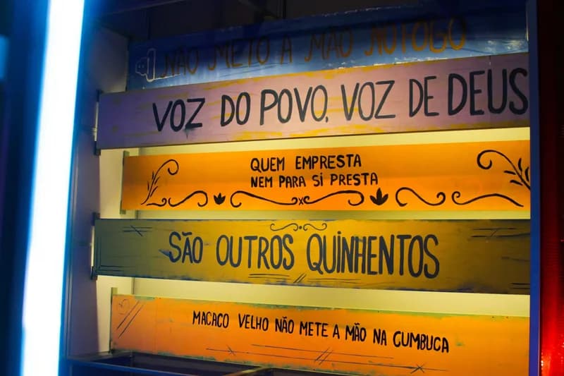 Tábuas pintadas com provérbios populares expostas em painel na exposição O Tempo Eu e Vc, case HOUSECULTURA