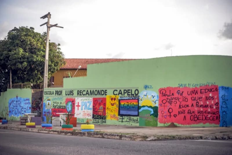 Fachada de escola pública pintada de verde com painéis e frases nas paredes, case HOUSECULTURA